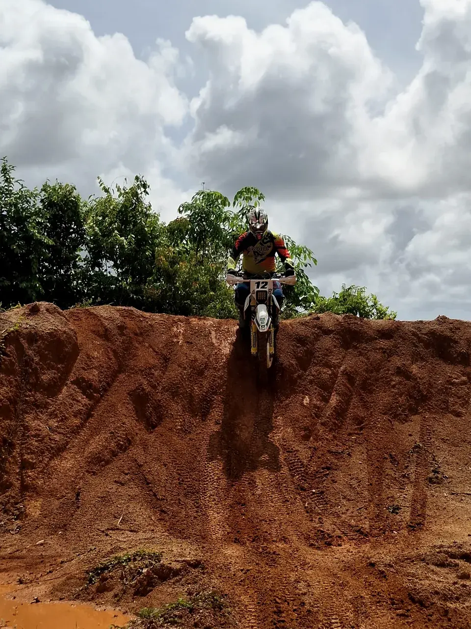 A rider starts down a steep red-clay drop in the Phuket hills
